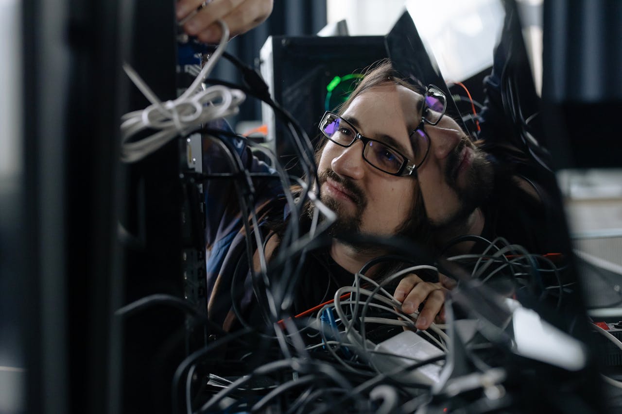 services-04 A skilled IT technician organizing tangled cables at his workstation in an office environment.