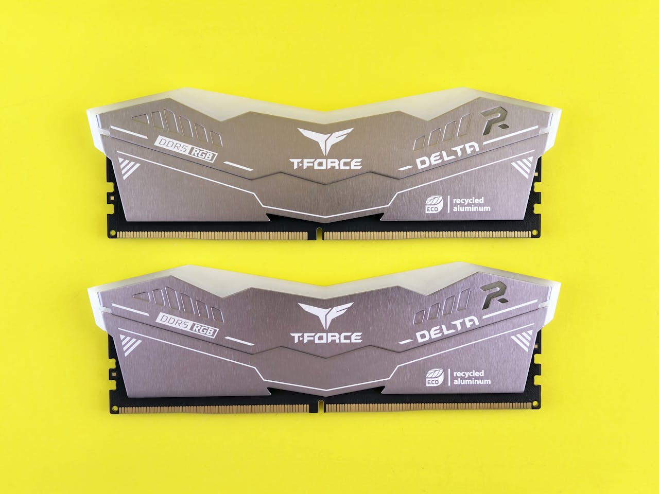 Close-up of two T-Force Delta DDR5 RGB memory sticks on a vibrant yellow background.